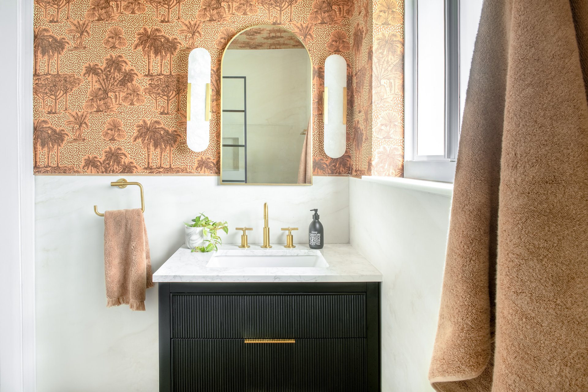 Powder room with palm-print wallpaper and fluted black vanity