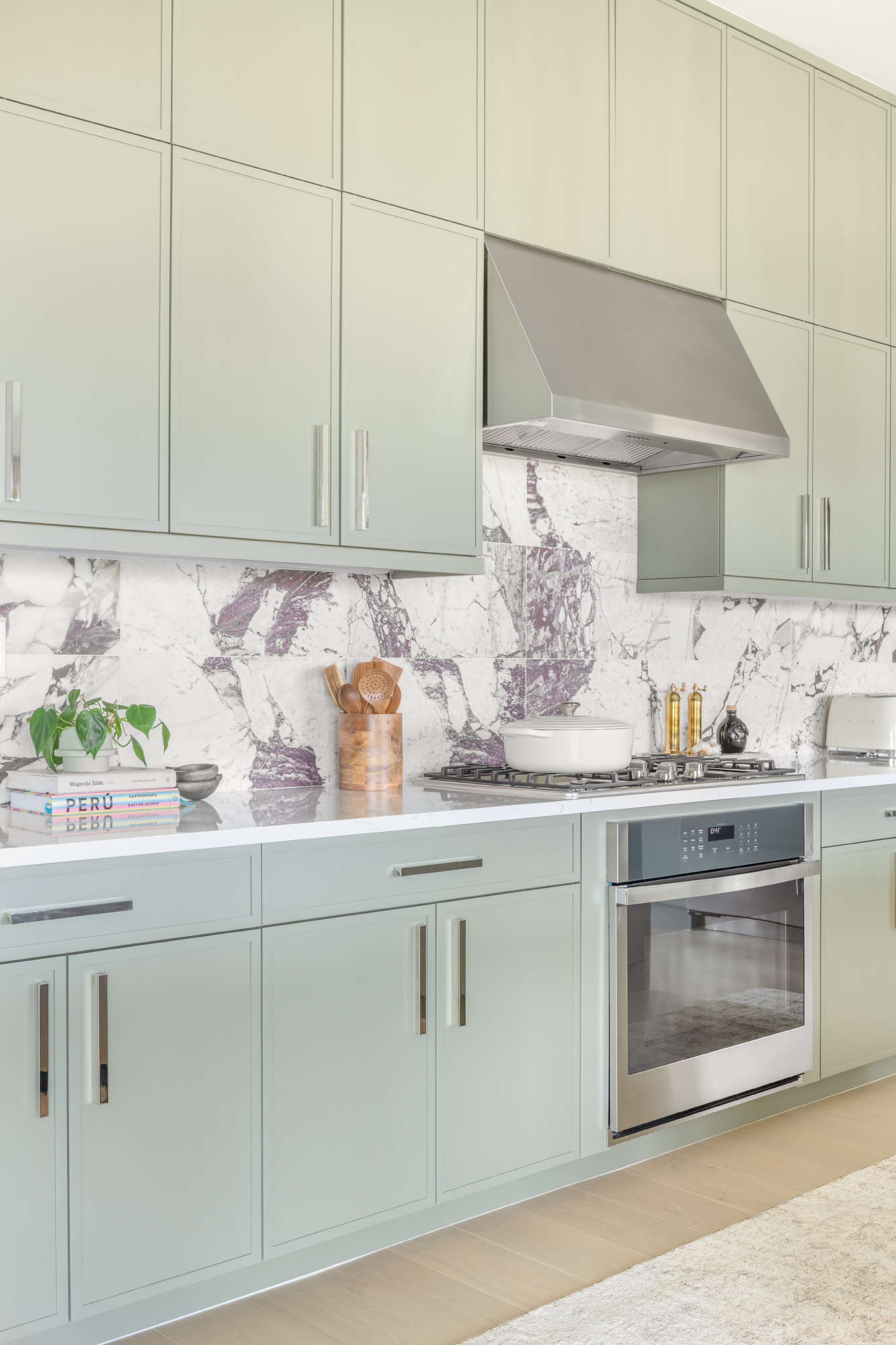 Sage green kitchen with veined marble backsplash and brass accents