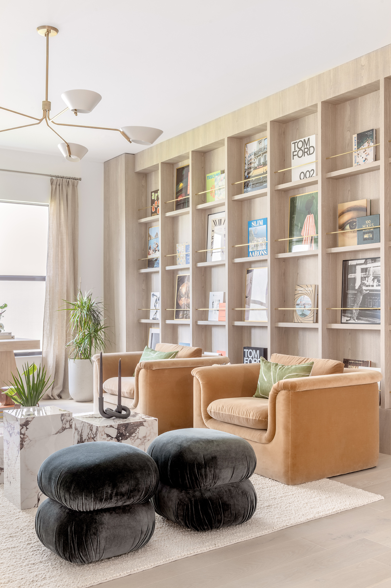 Library lounge with floor-to-ceiling oak shelving and camel velvet chairs