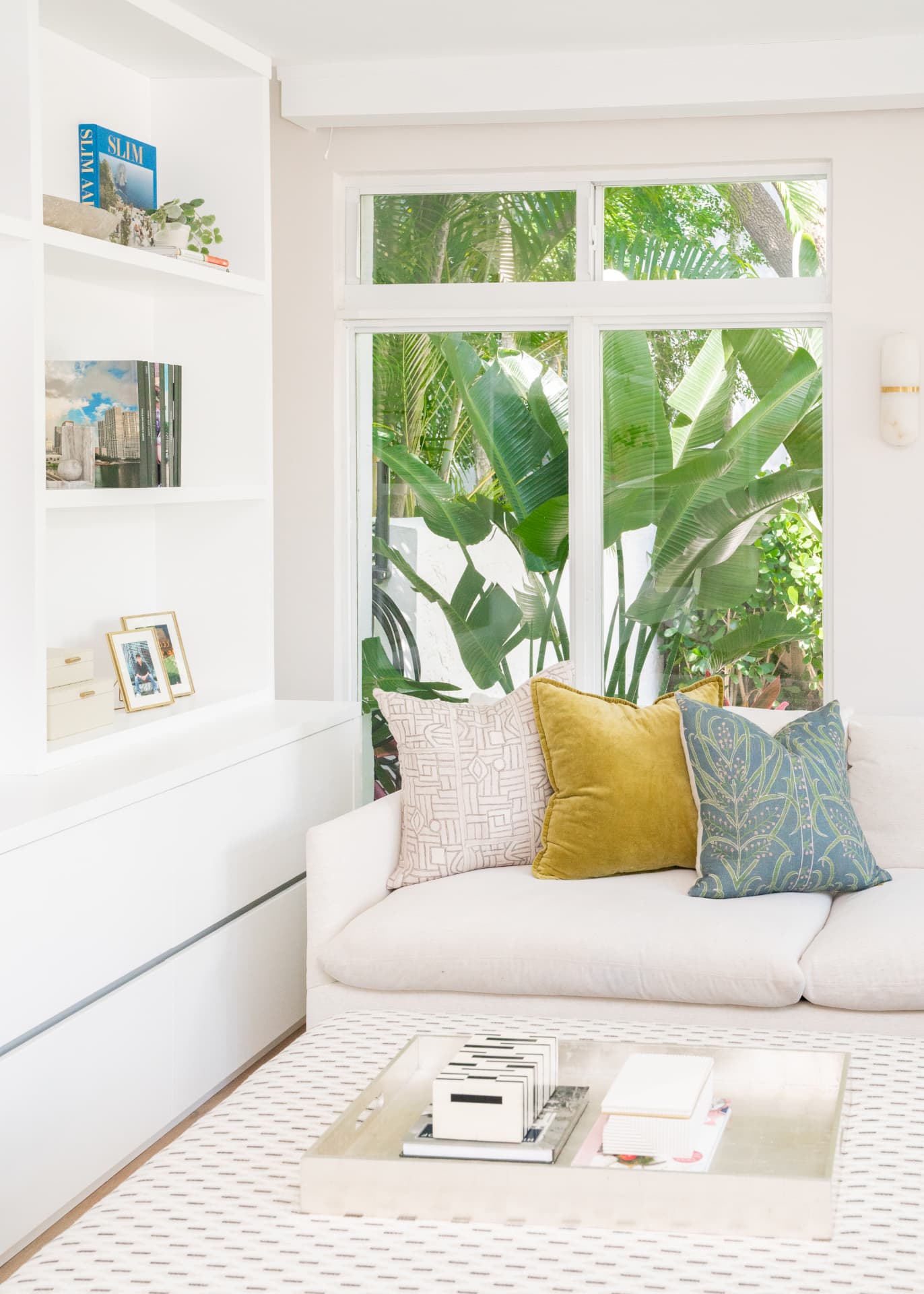 Sunlit window seat with patterned pillows and tropical greenery